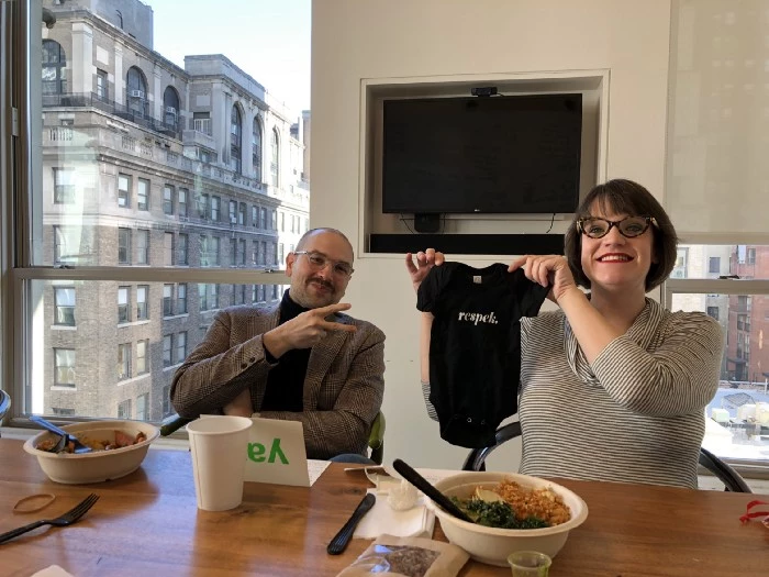 Man and woman at conference table holding onsie