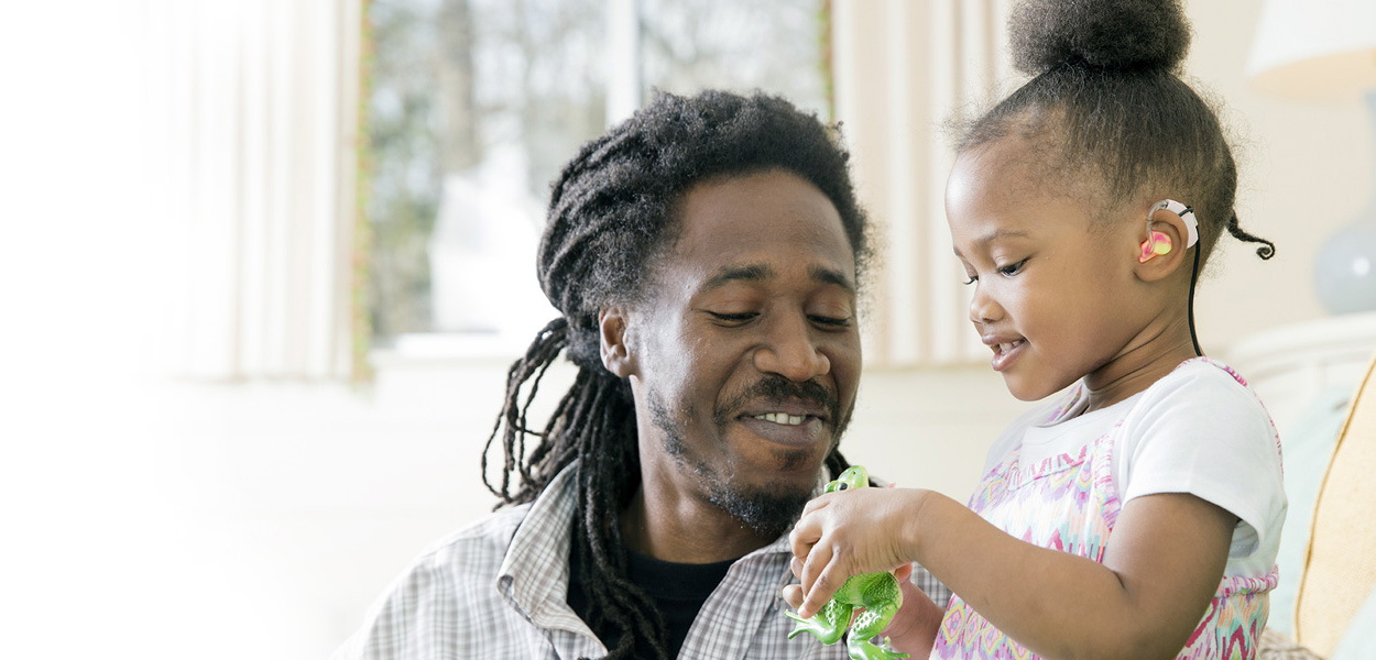 parent and child with hearing technology playing